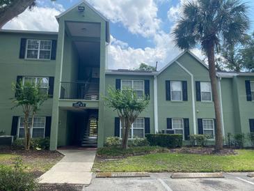Condo building with green exterior, black shutters, and tropical landscaping at 2007 Dixie Belle Dr # 2007 M, Orlando, FL 32812