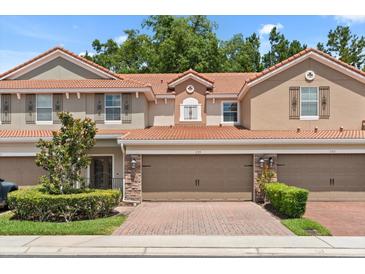 Inviting two-story townhouse features a red tile roof, two-car garage, and beautifully maintained landscaping at 299 Terracina Dr, Sanford, FL 32771