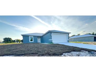 A charming single-story home with a well-manicured lawn, light-blue exterior and a two-car garage at 534 Central Ave, Frostproof, FL 33843