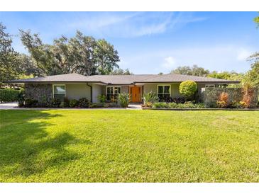 Charming single-story home featuring a well-manicured lawn, stone accents, and an inviting orange front door at 5370 Whispering Pine Cir, St Cloud, FL 34771