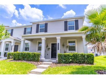 Charming two-story home featuring a covered porch, gray stucco, and lush, landscaped front yard at 15030 Book Club Rd, Winter Garden, FL 34787