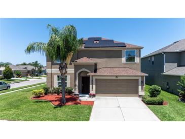 Inviting two-story home with a well-manicured lawn, solar panels, and an attached two-car garage at 1902 Hailsham Ct, Orlando, FL 32824