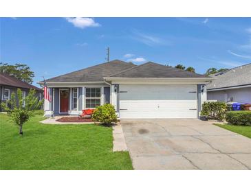 Charming single-Gathering home features a two-car garage, lush lawn, and a welcoming red front door at 204 Bay Meadow Dr, Kissimmee, FL 34746