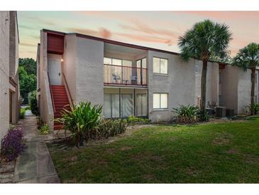 Inviting condo exterior featuring a private balcony, lush landscaping, and vibrant green lawn at 2486 Citrus Club Ln # 408, Orlando, FL 32839