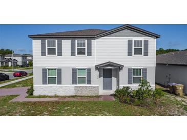 Charming two-story home with gray siding, stone accents, and well-maintained landscaping, offering great curb appeal at 596 Sun Warbler Way, St Cloud, FL 34771