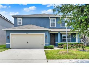 Charming two-story home featuring a two-car garage, blue siding, and well-manicured landscaping at 5967 Churchill Square Way, Groveland, FL 34736