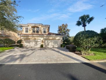 Two-story home with a two car garage and a brick paved driveway under a bright blue sky at 84 Camino Real Blvd, Howey In The Hills, FL 34737