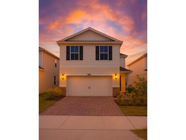 Charming two-story home with a two-car garage, brick driveway, and beautiful sunset sky at 10245 Park Estates Ave, Orlando, FL 32836