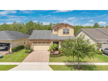 Charming two-story home featuring a well-manicured lawn, brick driveway, and inviting curb appeal at 14078 Alafaya Oak Bnd, Orlando, FL 32828