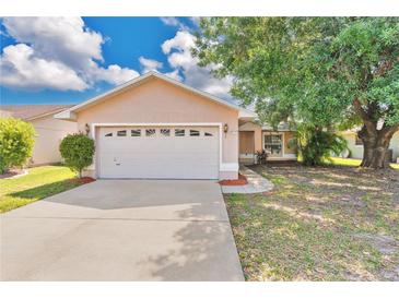 Charming single-story home with a two-car garage, well-maintained lawn, and mature shade tree at 1614 Christa Ct, St Cloud, FL 34772