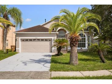 Charming single-Gathering home with a two-car garage, manicured lawn, and mature palm trees at 2506 Aster Cove Ln, Kissimmee, FL 34758