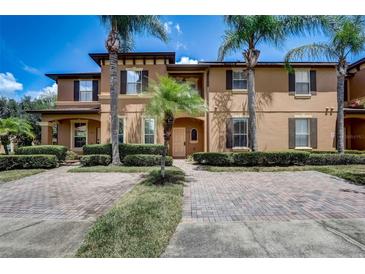 Inviting townhome featuring a brick driveway and beautiful landscaping, including mature palm trees for a tropical feel at 528 Terra Lago St, Davenport, FL 33897