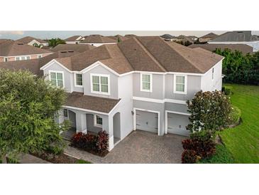 Two-story gray home featuring a brown roof, lush landscaping, and a two-car garage at 14572 Black Quill Dr, Winter Garden, FL 34787