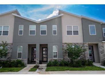 Modern townhome exterior boasts gray siding, stone accents, and a well-maintained landscaped front yard at 2379 Distant Sun Trl, Kissimmee, FL 34747