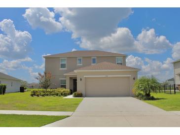 Inviting two-story home featuring a well-manicured lawn, complemented by lush greenery and a spacious two-car garage at 356 Quarry Rock Cir, Kissimmee, FL 34758