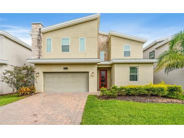 Contemporary two-story home boasts stone accents, a two-car garage, and a well-manicured lawn at 8833 Cruden Bay Ct, Davenport, FL 33896