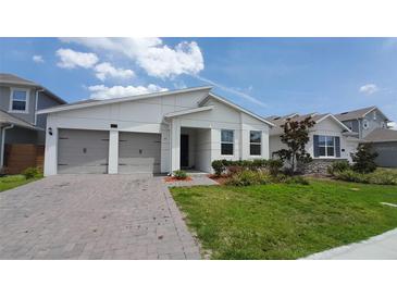 Charming single-story home with a two-car garage, manicured lawn, and modern architectural style at 14741 Milfoil Ave, Orlando, FL 32827