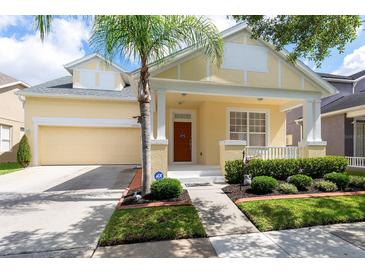 Charming yellow home featuring a manicured lawn, a two-car garage, and inviting front porch at 14741 Sapodilla Dr, Orlando, FL 32828