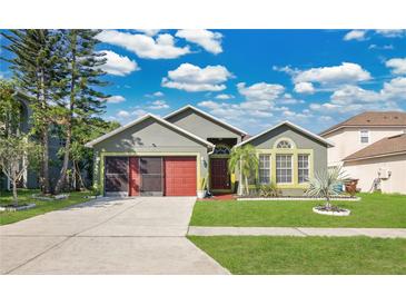 Charming home featuring a well-maintained lawn, red garage door, and lush landscaping at 321 Thomasdale Ave, Haines City, FL 33844