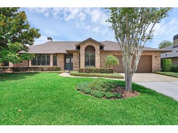 Charming brick home featuring a well-manicured lawn and mature landscaping, creating excellent curb appeal at 633 N Longview Pl, Longwood, FL 32779