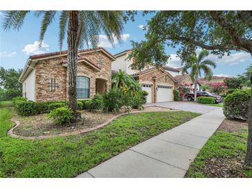 Beautiful two-story home with stone facade, red tile roof, tropical landscaping, and a two-car garage at 9736 Hatton Cir, Orlando, FL 32832