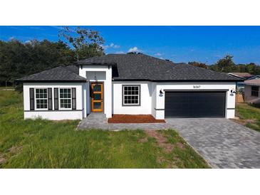 Charming single-Gathering home boasts a modern design with a brick-paved driveway and a black two-car garage at 16367 Sw 17Th Terrace Rd, Ocala, FL 34473