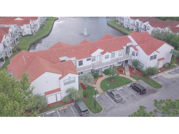 Overhead shot showcasing a condo with red tile roof, parking, and a scenic waterfront view with a fountain at 2536 Woodgate Blvd # 202, Orlando, FL 32822