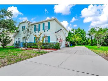 Charming two-story home featuring teal shutters, a well-manicured lawn, and an expansive driveway at 309 Black Springs Ln, Winter Garden, FL 34787