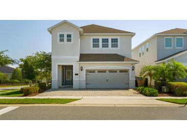 Charming two-story home featuring a gray garage door, brick driveway, and manicured landscaping at 341 Burma St, Kissimmee, FL 34747