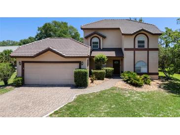 Charming two-story home with a tile roof, brick driveway, and lush green lawn at 4019 Lake Mirage Blvd, Orlando, FL 32817