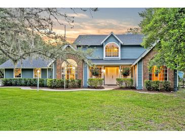 Charming two-story home with brick accents, lush green lawn, and manicured landscaping at 595 Seminole Woods Blvd, Geneva, FL 32732