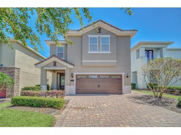 Two-story home showcasing a well-manicured front yard and a brick paved driveway leading to an attached garage at 640 Lasso Dr, Kissimmee, FL 34747