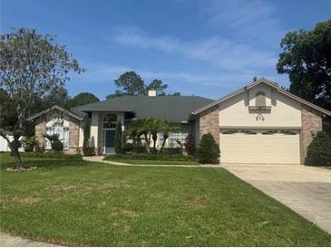 Charming single-Gathering home featuring a two-car garage, manicured lawn, and mature trees at 802 Kaywood Dr, Orlando, FL 32825