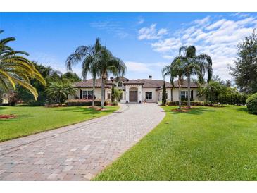 Stunning villa with a circular driveway, lush landscaping, and grand entrance at 10352 Burris Ct, Orlando, FL 32836