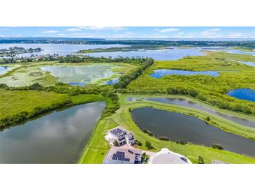 Stunning aerial view of the expansive property featuring multiple ponds and lush greenery, backing onto a large lake at 15208 Lake Claire Overlook Dr, Winter Garden, FL 34787