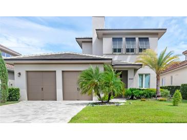 Beautiful home featuring a two-car garage, manicured lawn, and lush tropical landscaping at 15947 Vetta Dr, Bella Collina, FL 34756