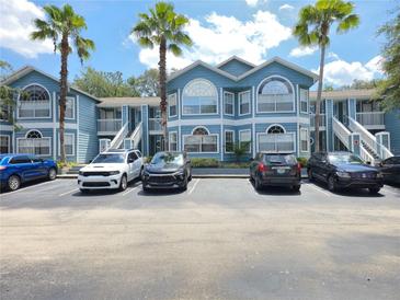Inviting condo complex with blue siding, palm trees, and convenient parking spaces at 3157 Britannia Blvd # B, Kissimmee, FL 34747