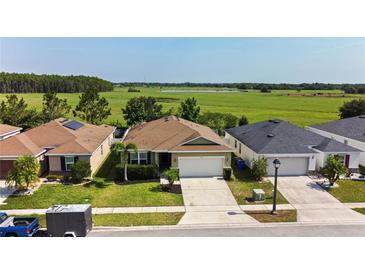 Charming single-story home featuring a well-manicured lawn and a view of a large open field in the back at 4553 Baler Trails Dr, St Cloud, FL 34772