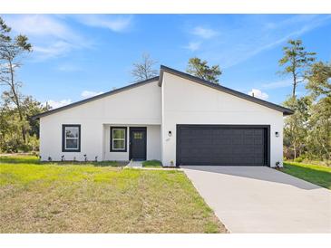 Charming single-story home featuring a modern white facade, black trim, and an attached two-car garage at 501 Marion Oaks Golf Way, Ocala, FL 34473
