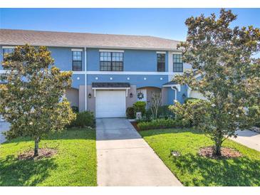 Charming townhome featuring a well-maintained lawn, attached garage, and attractive blue and beige exterior paint at 5420 Windsor Lake Cir, Sanford, FL 32773