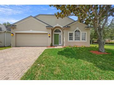 Charming single-story home featuring a well-manicured lawn and a neutral stucco exterior with a green front door at 714 Home Grove Dr, Winter Garden, FL 34787