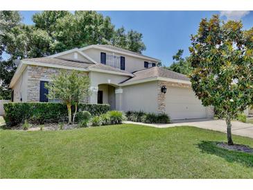 Charming two-story home with stone accents, manicured lawn, and mature landscaping under a clear blue sky at 9521 Southern Garden Cir, Altamonte Springs, FL 32714