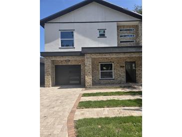 Modern two-story home boasts stone accents, black trim, and manicured landscaping for curb appeal at 1005 Randall St, Orlando, FL 32805
