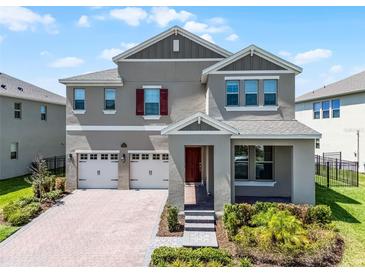 Stunning two-story home with a three-car garage, brick paver driveway, and manicured landscaping at 18309 Oliver Twist Way, Winter Garden, FL 34787