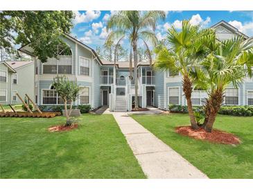 Charming two-story condo with light-blue siding, a well-manicured lawn, and mature trees creating a serene outdoor space at 2020 Royal Bay Blvd # 91, Kissimmee, FL 34746