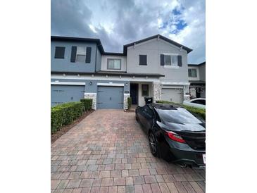 Stylish townhouse showcasing brick driveway and attached garages at 2937 Econ Landing Blvd, Orlando, FL 32825