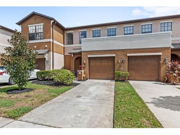 Inviting townhome with a well-manicured lawn, attached two-car garage, and neutral-tone exterior at 3331 Windsor Lake Cir, Sanford, FL 32773