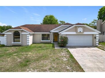 Charming one-story home with a well-manicured lawn, two car garage, and welcoming yellow front door at 7974 Village Green Rd, Orlando, FL 32818