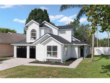 Charming two-story home features a black roof, white siding, black garage doors and manicured lawn at 9987 Triple Crown Cir, Orlando, FL 32825