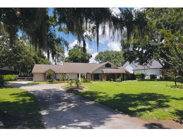 Charming single-story home with a lush green lawn and mature trees, offering a serene and inviting curb appeal at 11923 Lake Butler Blvd, Windermere, FL 34786